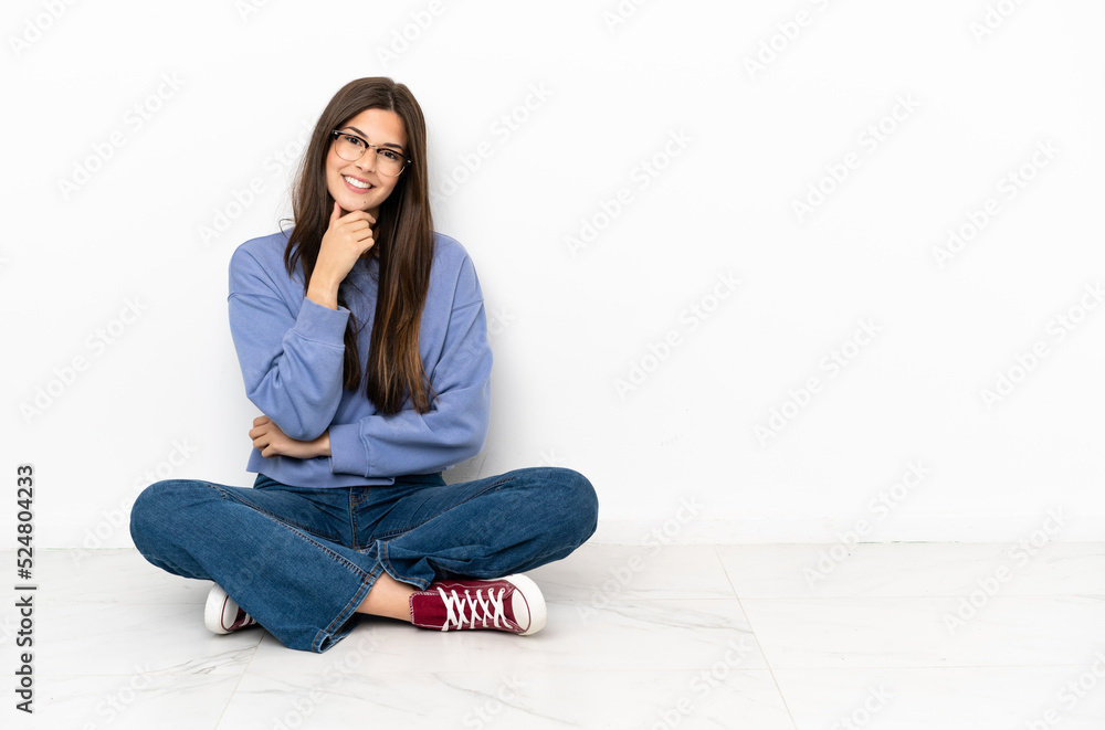Young woman sitting on the floor with glasses and smiling Young woman sitting on the floor with glasses and smiling