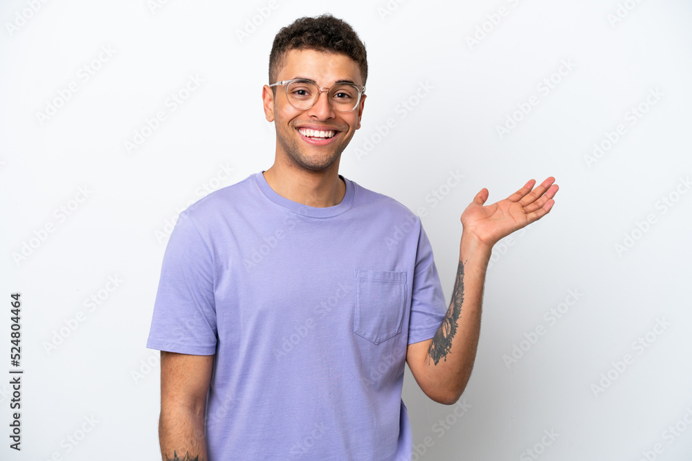 Young caucasian Brazilian man isolated on white background holding copyspace imaginary on the palm to insert an ad Young caucasian Brazilian man isolated on white background holding copyspace imaginary on the palm to insert an ad