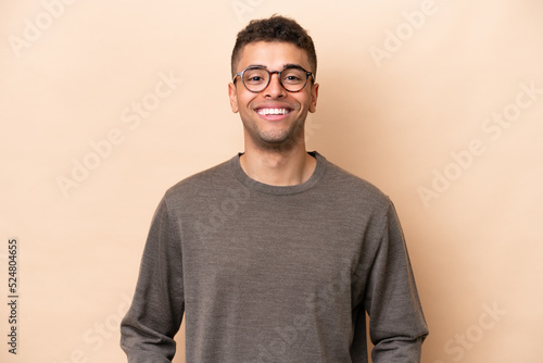 Young Brazilian man isolated on beige background laughing © luismolinero