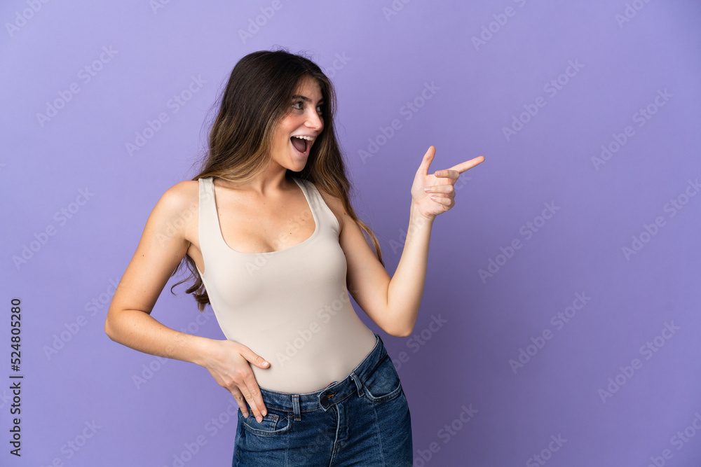 Young caucasian woman isolated on purple background pointing finger to the side and presenting a product Young caucasian woman isolated on purple background pointing finger to the side and presenting a product
