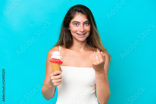 Young woman in swimsuit holding an ice cream isolated on blue background inviting to come with hand. Happy that you came © luismolinero