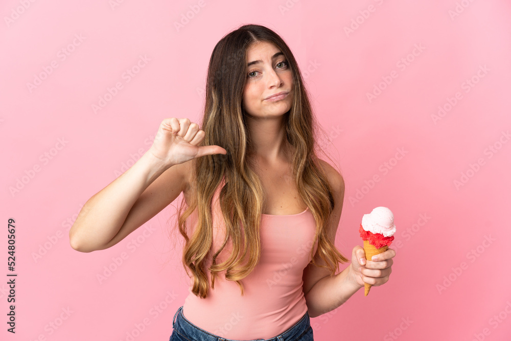 Young caucasian woman with a cornet ice cream isolated on pink background showing thumb down with negative expression Young caucasian woman with a cornet ice cream isolated on pink background showing thumb down with negative expression