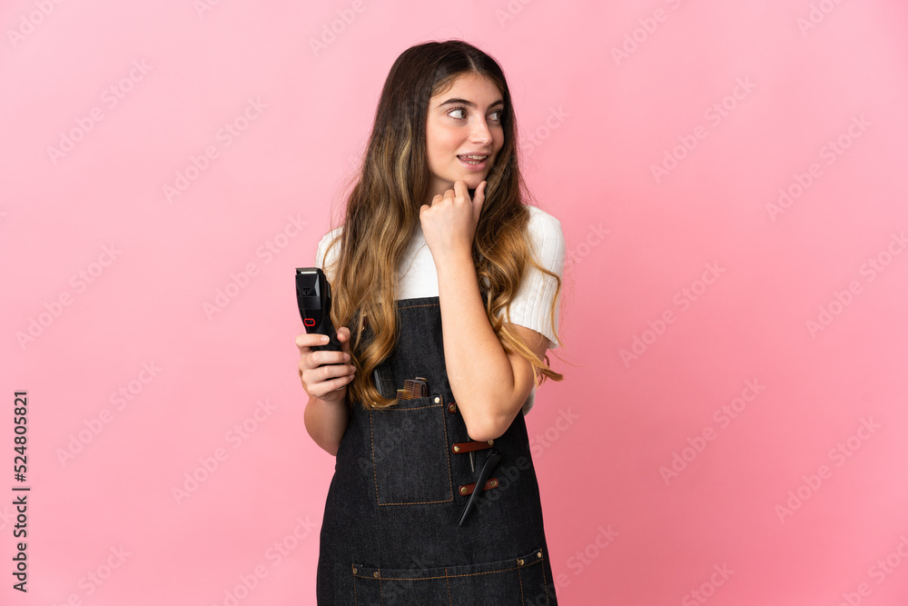Young hairdresser woman isolated on pink background looking to the side and smiling Young hairdresser woman isolated on pink background looking to the side and smiling