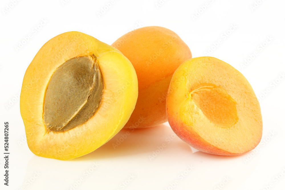 Whole and sliced apricots with visible core seed isolated on white background