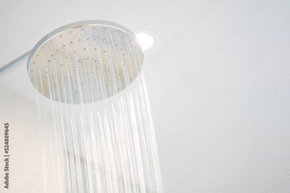 Water was pouring out from a large circular shower in the dimly lit bathroom that has a glass window and can see the view outside. Water was pouring out from a large circular shower in the dimly lit bathroom that has a glass window and can see the view outside.