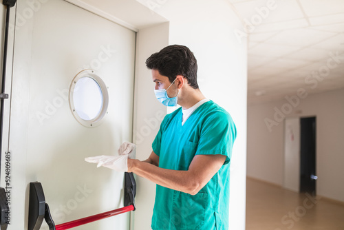 Doctor putting on sterile gloves in clinic hall photo
