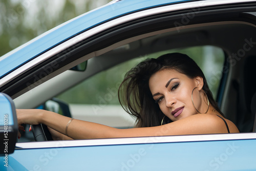 Black-haired woman driver shows confident poses and emotions grimacing in car. Businesswoman looks with self-confidence and satisfaction closeup © lenblr