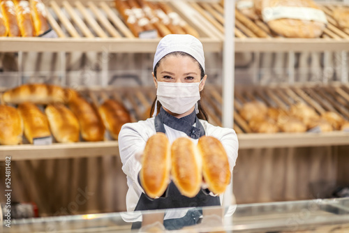 A bakery department saleswoman giving pastry to a customer in supermarket during covd 19. photo