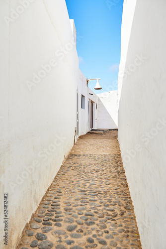 Narrow passage between white houses under blue sky photo