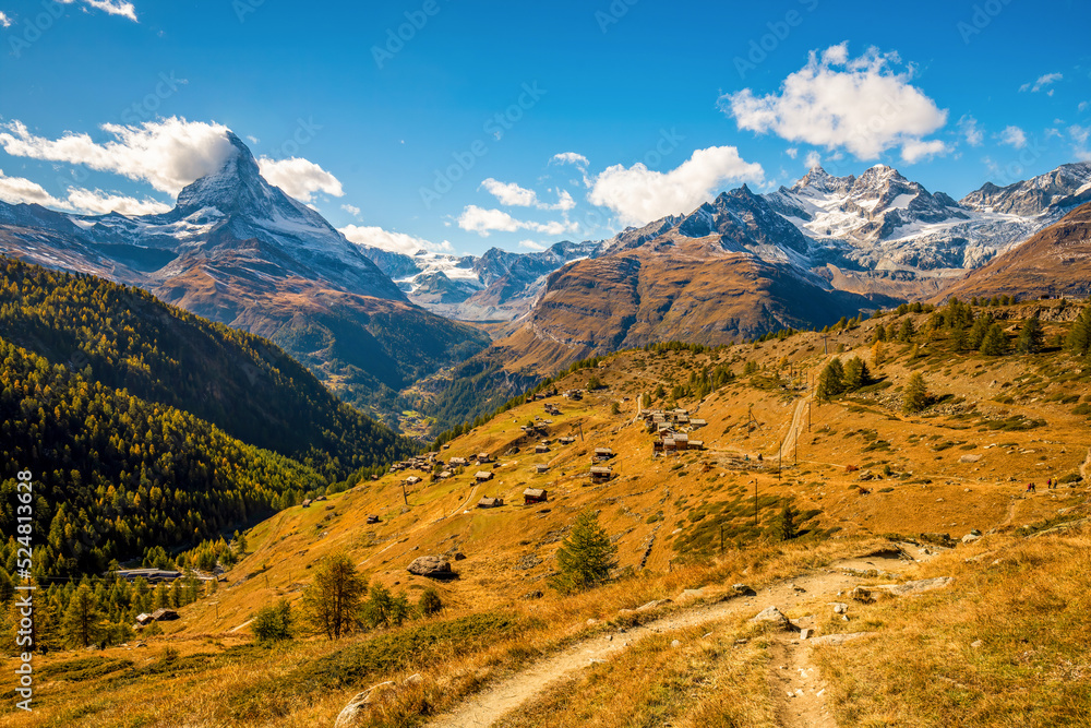Stunning autumn scenery of famous alp peak Matterhorn from Sunnegga area. Hiking trail among yellowed grass on foreground. Popular hiking route - 5 Lakes Walk. Swiss Alps, Valais, Switzerland