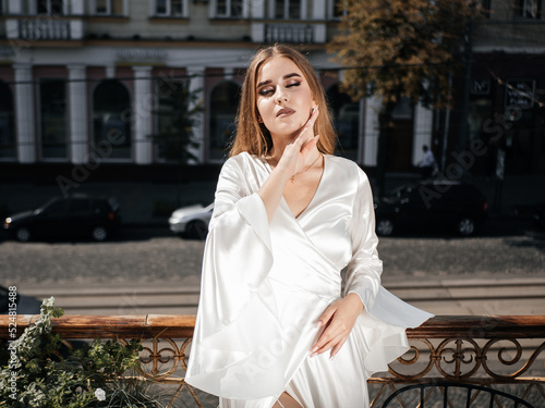 Obraz na płótnie A girl in a white dress poses on the balcony w salonie