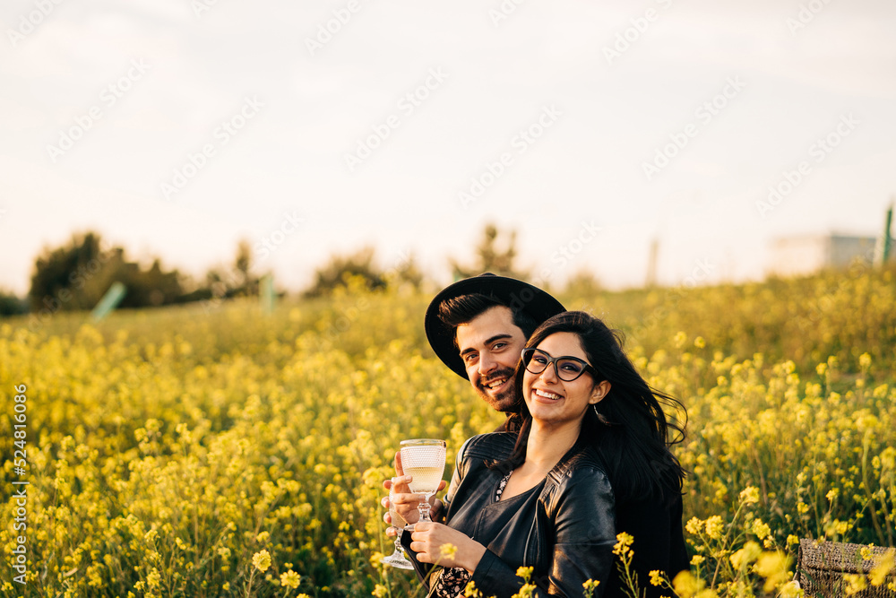 Ethnic couple with glasses of white wine on meadow Ethnic couple with glasses of white wine on meadow