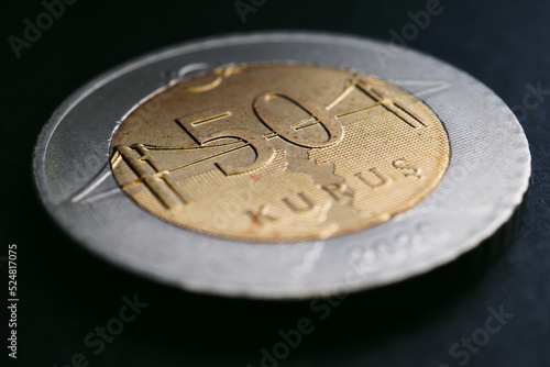 Translation: 50 kurus. Turkish coin of 50 kuruş lies on a black surface close up. National currency of Turkey. Illustration for news about currency or finance. Bosphorus Bridge. Macro