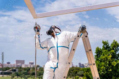 Unrecognizable worker painting building on sunny day photo