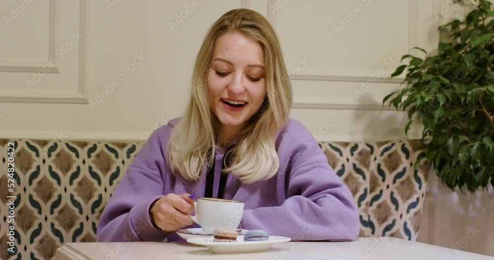 Blonde woman enjoys cup of coffee showing thumb-up gesture. Happy lady takes lunch break sitting at table in cozy cafe near pot-plant closeup Blonde woman enjoys cup of coffee showing thumb-up gesture. Happy lady takes lunch break sitting at table in cozy cafe near pot-plant closeup