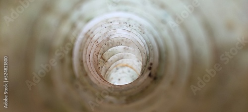 Deep white large and long dirty flexible endless round plastic pipe hole inside closeup view. Pipeline, tube, duct, drainage, sewage, sewer and mine concept. Abstract blurry background with copy space
