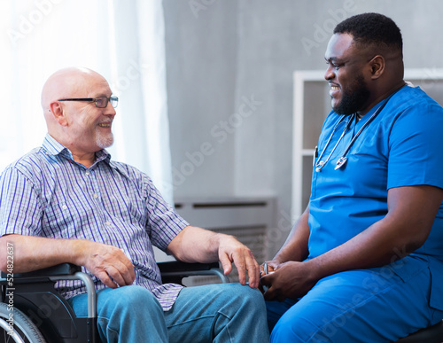 Professional doctor helps an elderly man with chronic diseases. Therapist and patient in home interior. Health care and medicine concept.