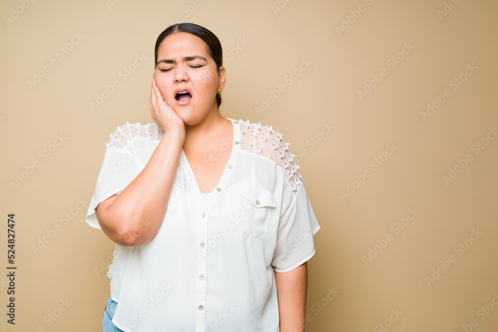 Sick obese woman feeling in pain because of a toothache Sick obese woman feeling in pain because of a toothache