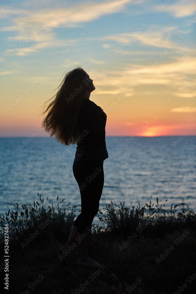 Portrait of a beautiful young girl at sunset against the background of nature and the sea.