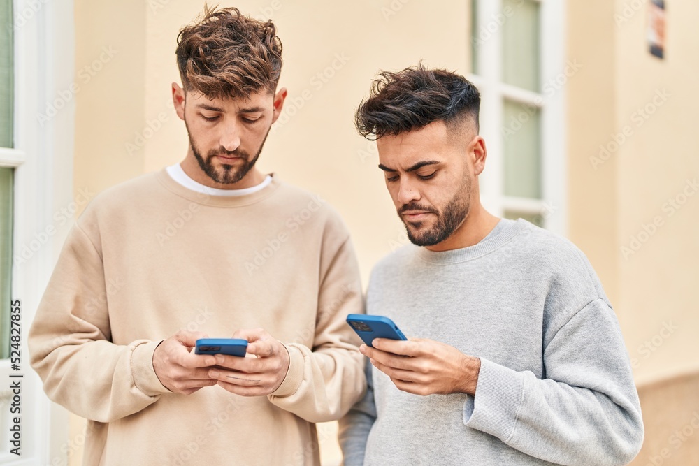 Young couple using smartphone standing together at street Young couple using smartphone standing together at street