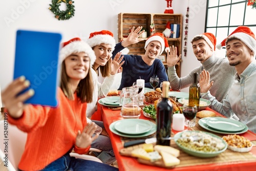 Group of young people having video call using laptop on christmas dinner at home.