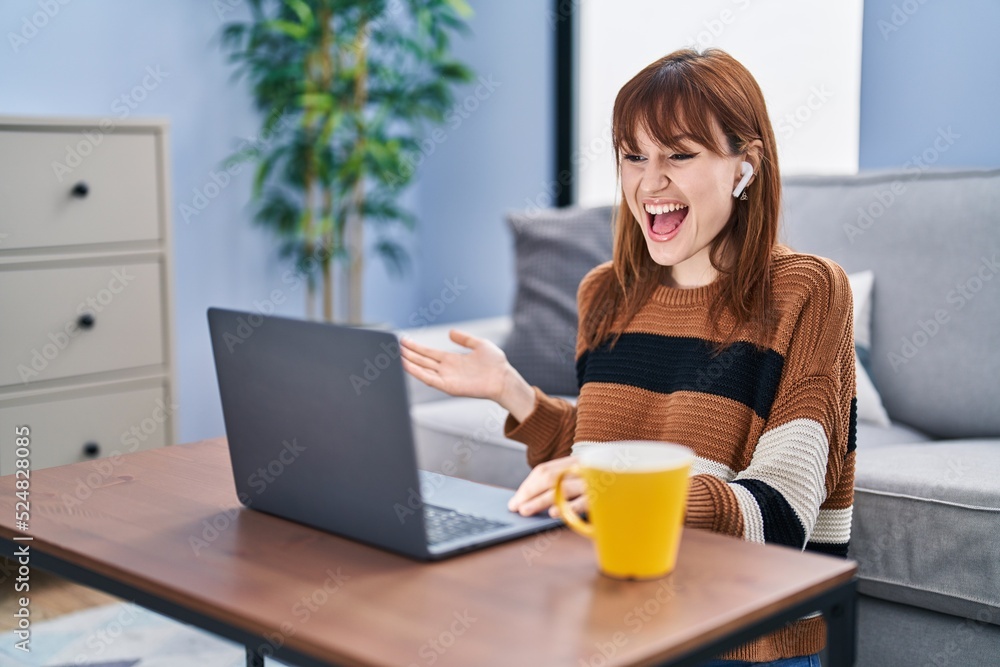 Young beautiful woman using computer laptop doing video call celebrating achievement with happy smile and winner expression with raised hand Young beautiful woman using computer laptop doing video call celebrating achievement with happy smile and winner expression with raised hand