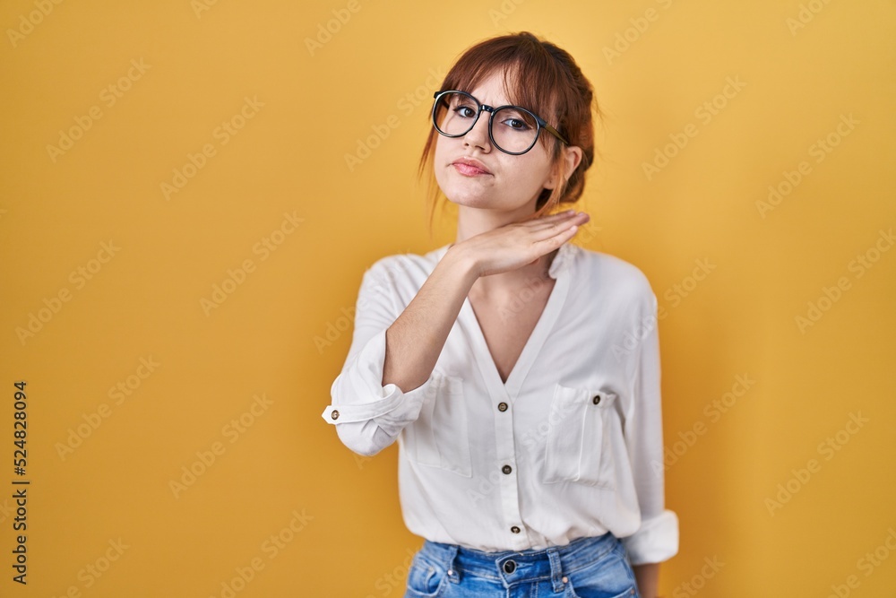 Young beautiful woman wearing casual shirt over yellow background cutting throat with hand as knife, threaten aggression with furious violence