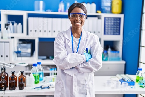 Young african american woman scientist smiling confident standing with arms crossed gesture at laboratory