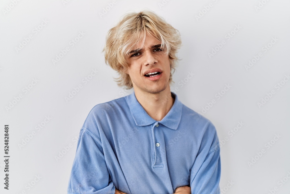 Young modern man standing over isolated background skeptic and nervous, disapproving expression on face with crossed arms. negative person. Young modern man standing over isolated background skeptic and nervous, disapproving expression on face with crossed arms. negative person.