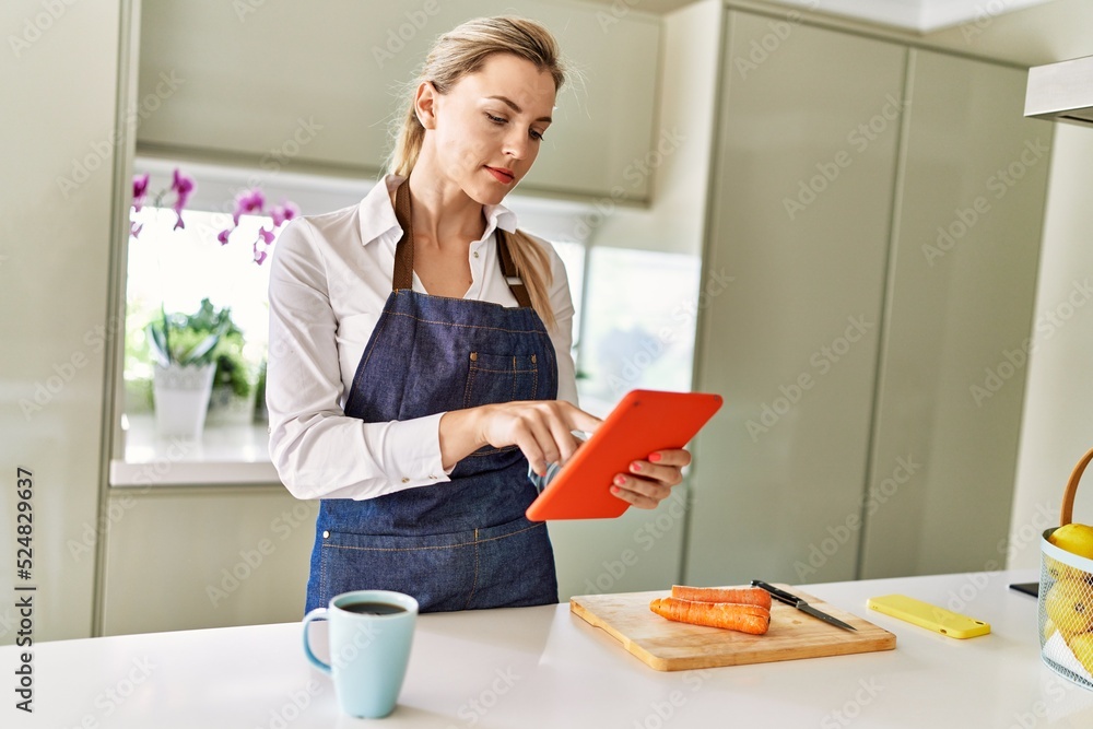 Young blonde woman using touchpad at kitchen Young blonde woman using touchpad at kitchen