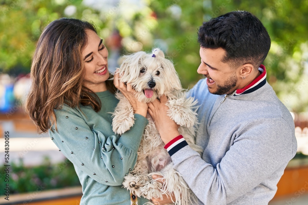 Man and woman holding dog standing together at park Man and woman holding dog standing together at park