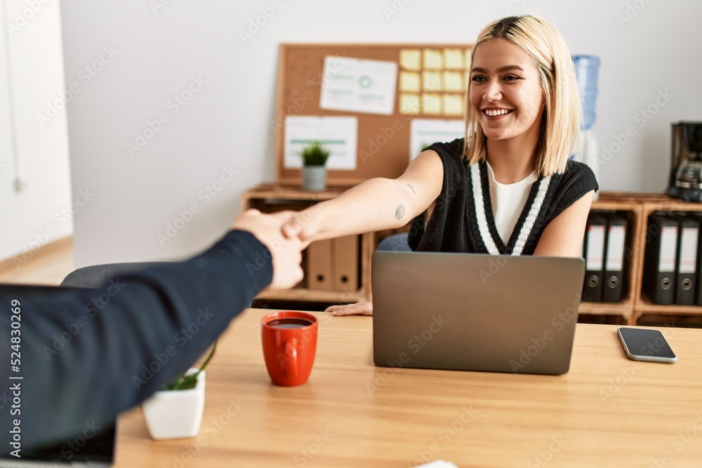 Two business workers smiling happy shaking hands at the office. Two business workers smiling happy shaking hands at the office.