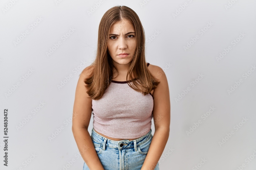 Obraz premium Young brunette woman standing over isolated background skeptic and nervous, frowning upset because of problem. negative person.
