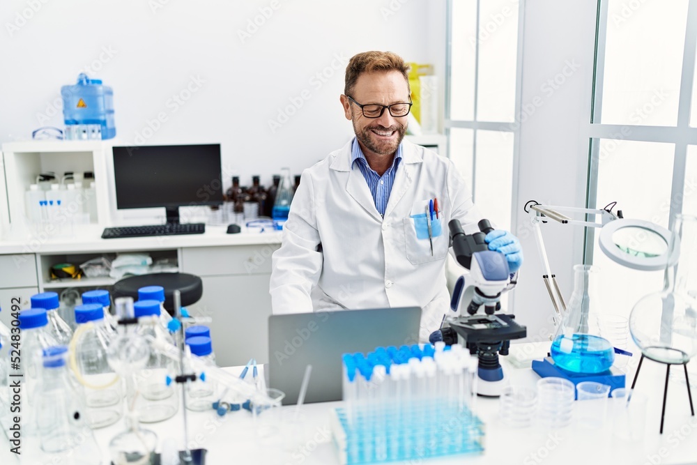 Fototapeta premium Middle age hispanic man wearing scientist uniform working at laboratory
