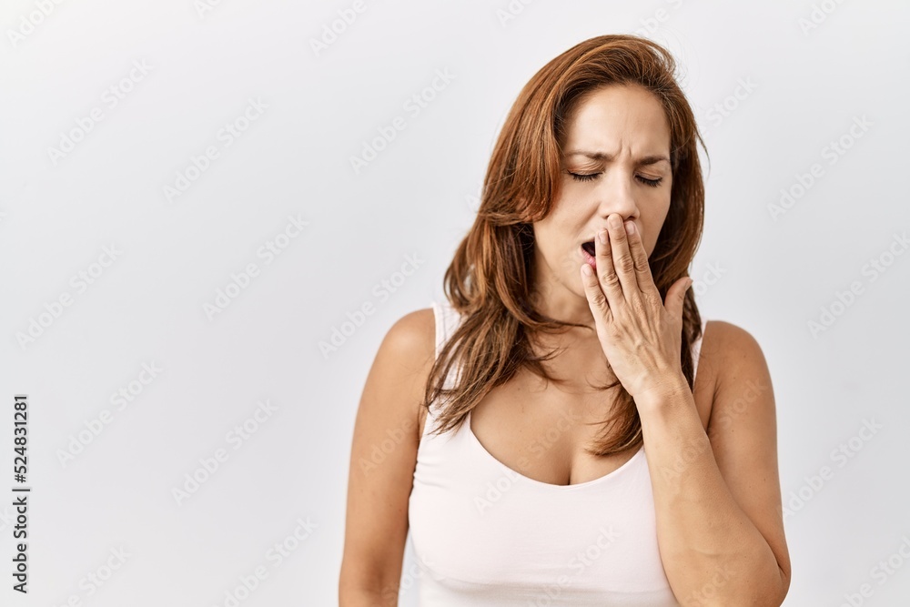 Middle age hispanic woman standing over isolated background bored yawning tired covering mouth with hand. restless and sleepiness. Middle age hispanic woman standing over isolated background bored yawning tired covering mouth with hand. restless and sleepiness.