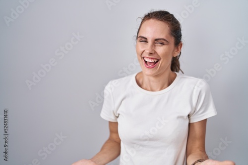 Beautiful brunette woman standing over isolated background smiling cheerful with open arms as friendly welcome, positive and confident greetings