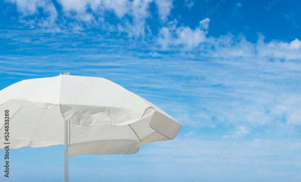 White beach umbrella against blue sky with copy space.