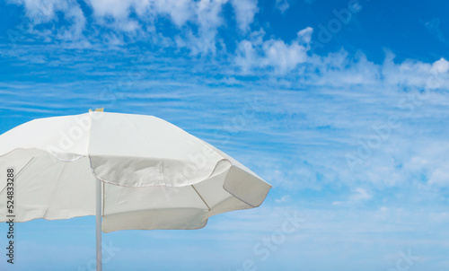 White beach umbrella against blue sky with copy space. © salarko