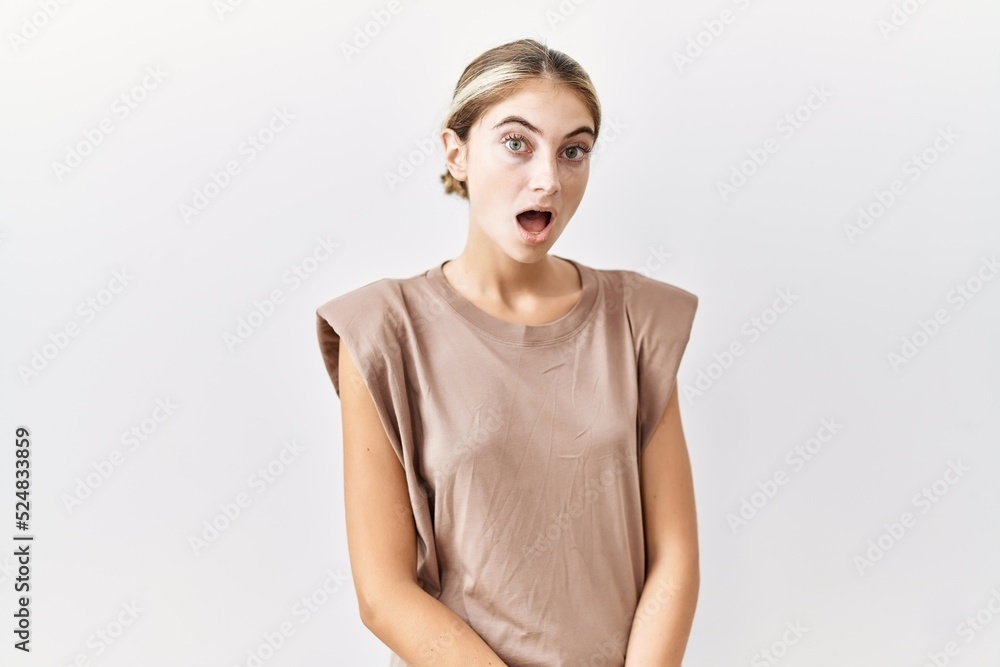 Young blonde woman standing over isolated background afraid and shocked with surprise expression, fear and excited face. Young blonde woman standing over isolated background afraid and shocked with surprise expression, fear and excited face.