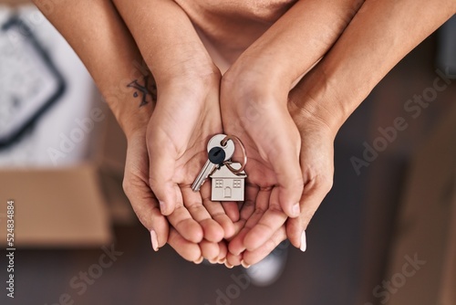 Woman and girl mother and daughter hands holding key at new home