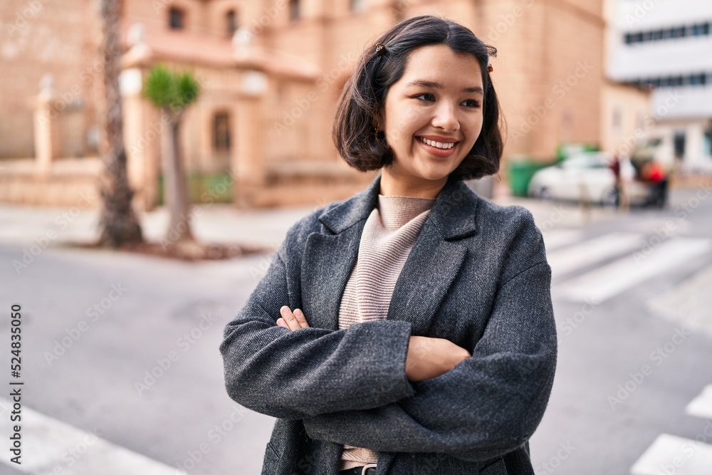 Young woman standing with arms crossed gesture looking to the side at street