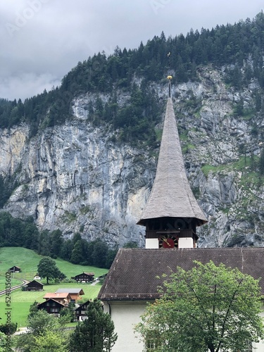 Fototapeta Naklejka Na Ścianę i Meble -  Beautiful church in Lauterbrunnen valley, Swiss Alps, Switzerland, summer 2022. Scenic Lauterbrunnen mountain landscape, a village, woodwn houses, cathedral and high grey mountains with trees