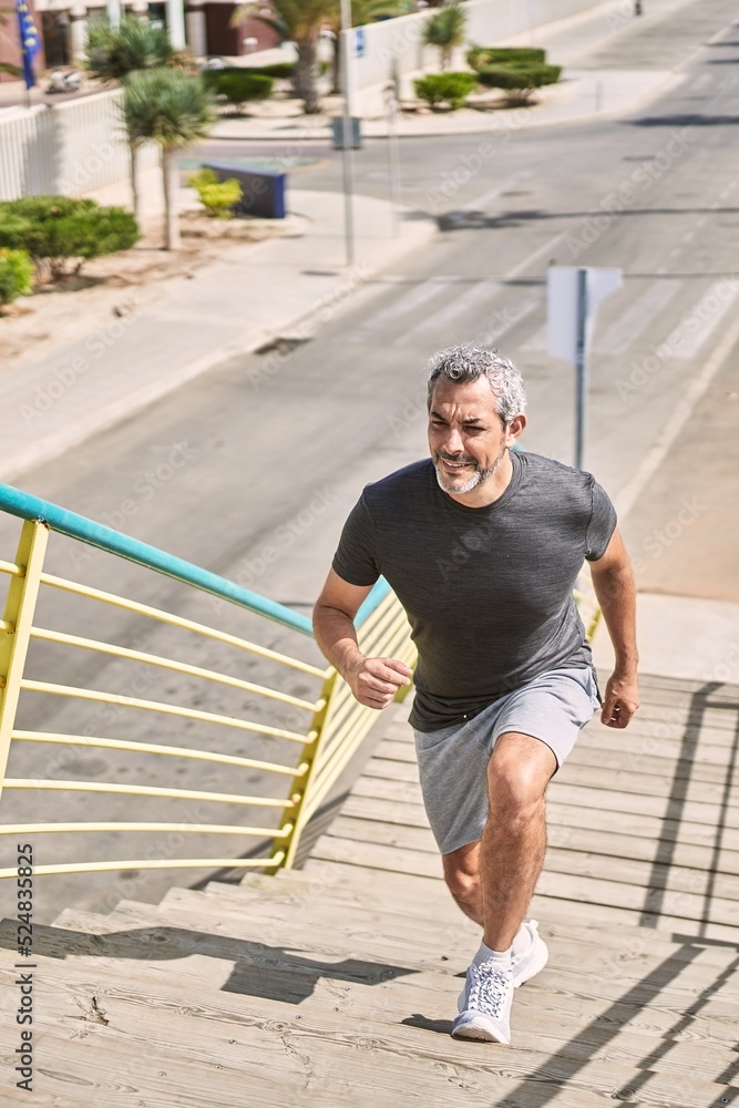 Middle age hispanic man wearing sportswear running at street