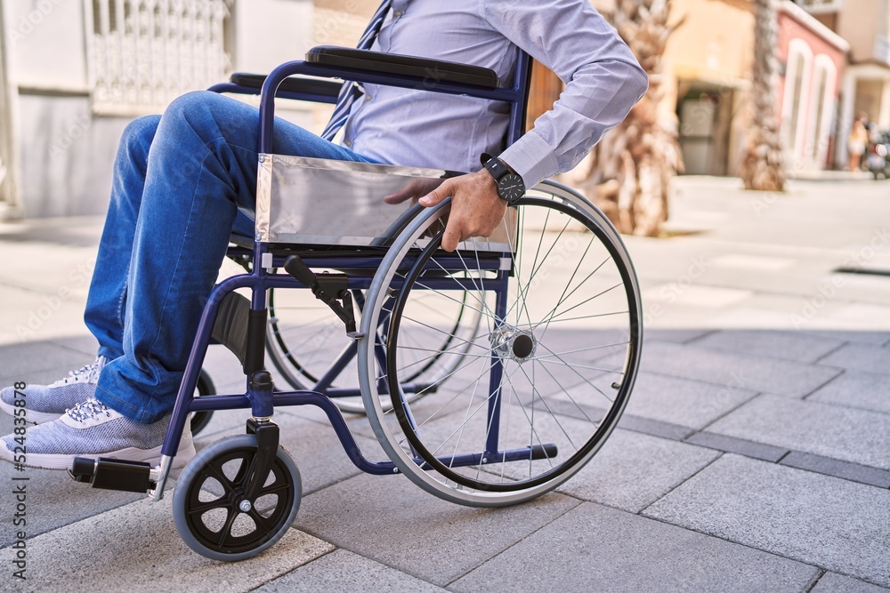 Obraz premium Middle age hispanic man wearing business clothes sitting on wheelchair at street