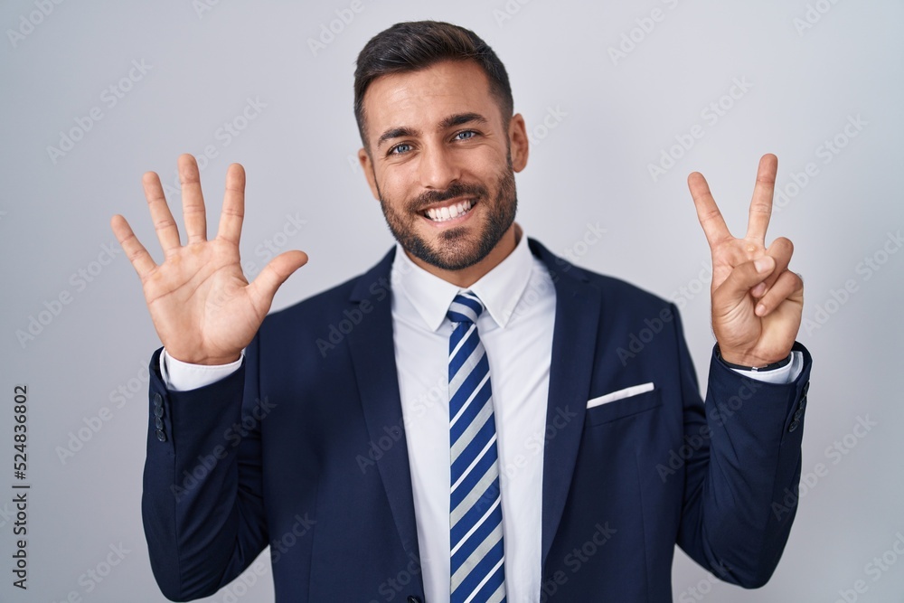 Handsome hispanic man wearing suit and tie showing and pointing up with fingers number seven while smiling confident and happy. Handsome hispanic man wearing suit and tie showing and pointing up with fingers number seven while smiling confident and happy.