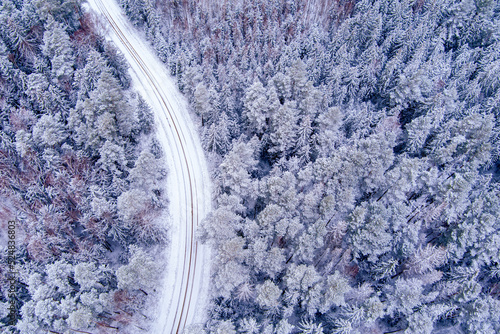Aerial view of snow covered forest with road as seen from drone © Ints