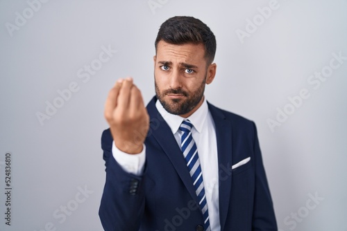 Handsome hispanic man wearing suit and tie doing italian gesture with hand and fingers confident expression