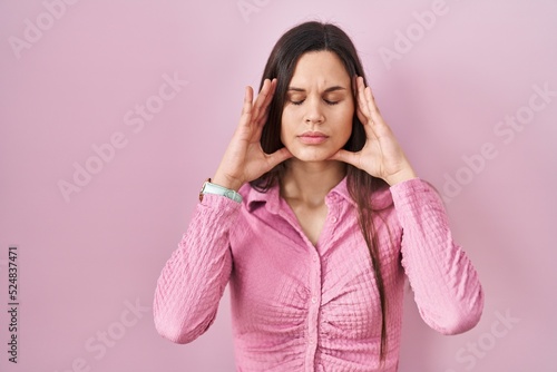 Young hispanic woman standing over pink background with hand on head, headache because stress. suffering migraine. © Krakenimages.com