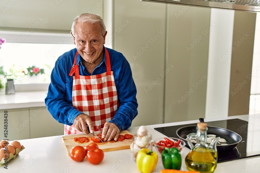 Senior man smiling confident cutting tomato at kitchen Senior man smiling confident cutting tomato at kitchen