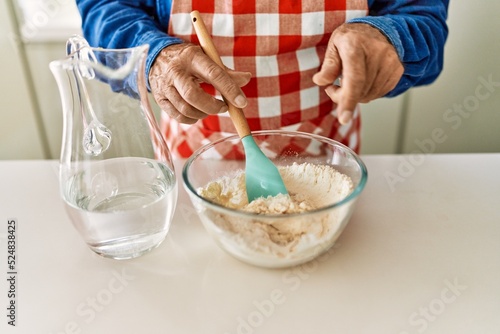 Senior man cooking dough at kitchen